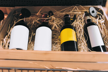 Wine bottles with blank labels in wooden box with straw.