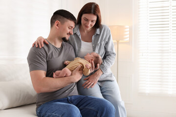 Happy parents with their cute newborn baby indoors, space for text