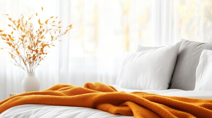 A cozy bedroom scene featuring a soft orange blanket draped over a plush white bed, creating a warm and inviting atmosphere perfect for relaxation and comfort.