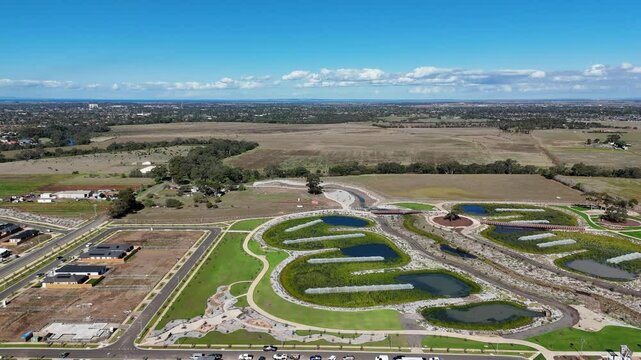 Aerial drone view of Tarneit, Melbourne’s expanding suburban fringe in Australia, showing new housing developments beside engineered wetlands and open paddocks.