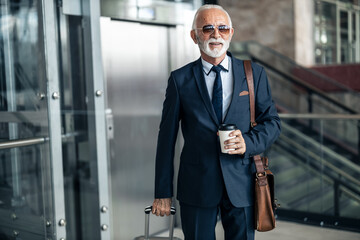 Senior Businessman Travel Ready with Coffee and Luggage