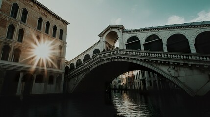 Naklejka premium The Rialto Bridge in Venice at sunrise, its architectural beauty highlighted by soft, warm light and the sky reflecting in the water below. 
