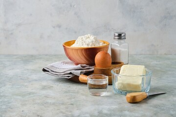 Ingredients for making shortcrust pastry on a gray concrete background. Different types of dough.