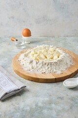 Kneading shortcrust pastry by hand on a wooden board on a grey concrete background. Different types of dough and their preparation techniques.