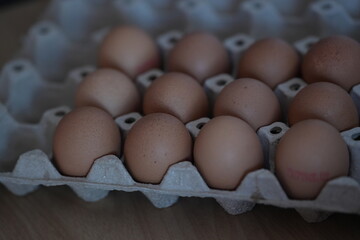 Brown chicken eggs neatly arranged in a paper tray, ready to be used for cooking.