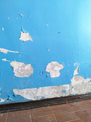 Old entrance of residential building. Cracked blue paint on wall. Dirty floor. Cleaning concept. Peeling painted background. House renovation. Repair. Reconstruction. housing and communal service