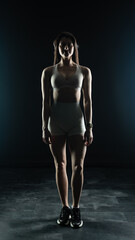 Young beautiful woman with athletic body on dark background. Fitness girl