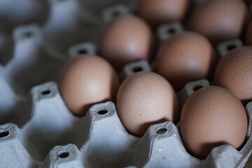 Brown chicken eggs neatly arranged in a paper tray, ready for cooking