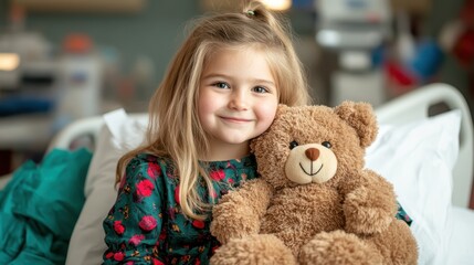 A young girl sitting in a hospital bed, smiling brightly while holding a fluffy teddy bear, showcasing a moment of comfort and joy during a challenging time in her life.