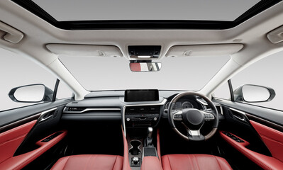 Right-hand drive luxury car interior with red leather. Car front panel wide angle view: seats, steering wheel, dashboard and center console, white headliner and sunroof. Camden, UK - April 18 2020.