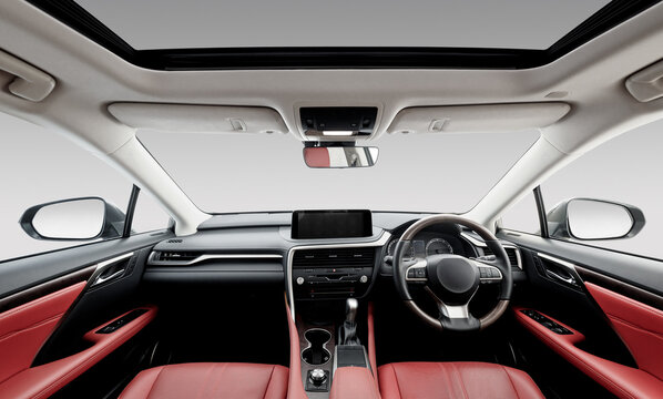 Right-hand drive luxury car interior with red leather. Car front panel wide angle view: seats, steering wheel, dashboard and center console, white headliner and sunroof. Camden, UK - April 18 2020.