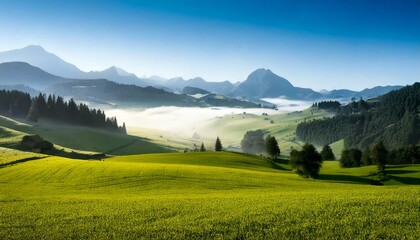Paisaje de valle brumoso con campo verde y monta&ntilde;as brumosas; hermoso fondo de pantalla matutino; fondo pintoresco inspirador para pancartas o postales, espacio de copia, dise&ntilde;o de lugar, inspiraci&oacute;n