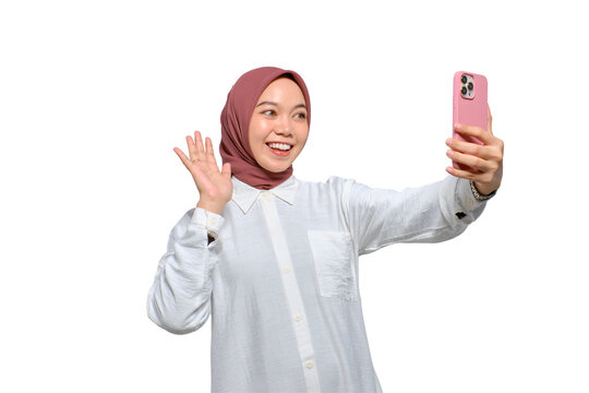 Cheerful young Asian Muslim woman with smartphone making video call or taking selfie isolated on transparent background