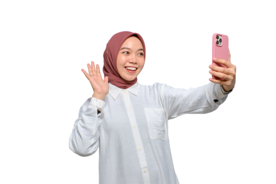 Cheerful young Asian Muslim woman with smartphone making video call or taking selfie isolated on transparent background