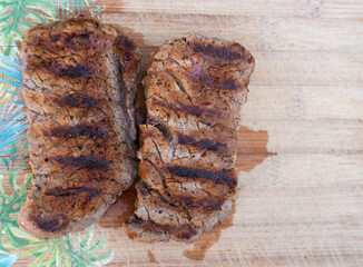 Delicious Grilled Steak Presented on a Wooden Surface with Flavorful Seasoning and Garnish