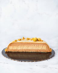 French Style Praline Mousse Cake Cut in Half. Clean Front View on White Marble Background.