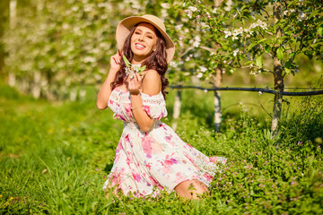portrait of a beautiful woman in a dress in a blooming apple orchard enjoying a sunny spring day