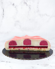 Artistic raspberry and white chocolate mousse cake with velvet texture and geometric cut. Cross-section showing layered filling on marble background. Ideal for editorial or branding use.