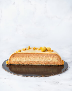 French Style Praline Mousse Cake Cut in Half. Clean Front View on White Marble Background.