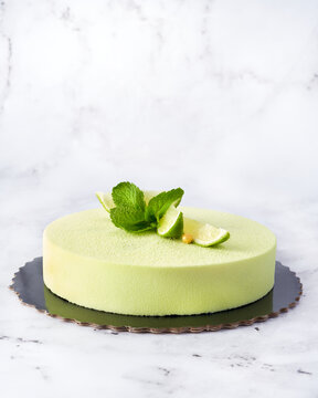 Green Mousse Cake with Lime and Mint. Front View on Marble Background with Copy Space.