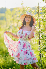 portrait of a beautiful woman in a dress in a blooming apple orchard enjoying a sunny spring day