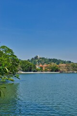 KANDY, SRI LANKA - FEBRUARY 10, 2021: View on Kandy lake and big Buddha on top of the hill. Kandy is home of The Temple of the Tooth Relic, one of the most sacred Buddhist places of worship. 