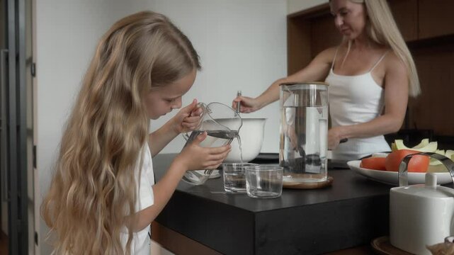 Caring youngest daughter pours water for her sisters in the kitchen, learning to help with household tasks. Mother observes proudly, enjoying her coffee, highlighting sisterly love and family bonding.
