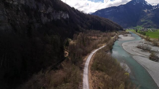 Road along river Linth in Switzerland woodland forest view of Swiss Alps mountains