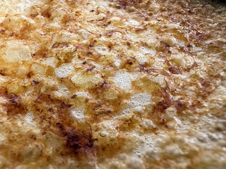 Delightful, golden-brown texture of a freshly cooked creme brulee. The surface showcases a delicious combination of crispy edges and tiny air bubbles