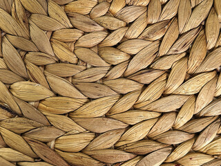 A close-up shot showcasing the intricate details of woven raffia fibers. Natural, earthy tones and textured surface create a warm aesthetic