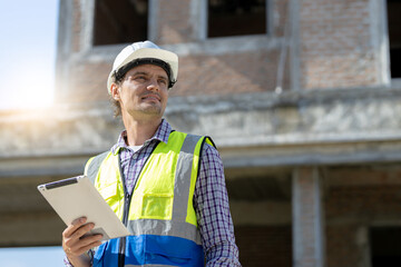 Engineers, Architects, Managers handsome caucasian man face holding a Tablet Construction of houses and buildings with confidence construction background.Free space banner,blue sky ,hard hat,vest