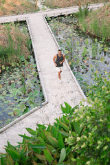 Sportsman running on concrete path in lush green park in Bangkok
