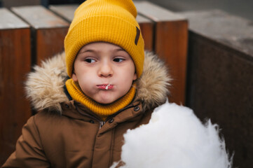 Cute baby boy eating cotton candy in the park.