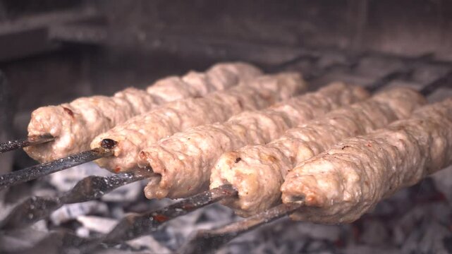 lula kebabs grilling on metal skewers, rotating for uniform browning over high heat, releasing savory aromas