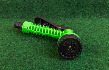 Green nozzle for watering the garden hose placed on grass