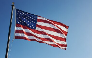 Fototapeta premium American Flag Waving Proudly Under a Clear Blue Sky