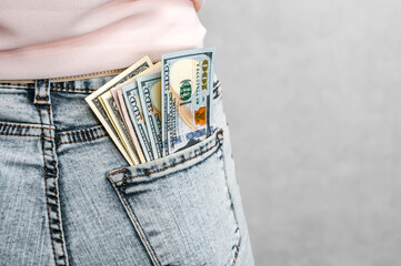 Close-up. American dollars in the back pocket of the girl's jeans. On a light background.