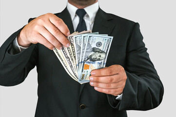 Close-up, American dollars money in the hands of a business man. White and gray background.