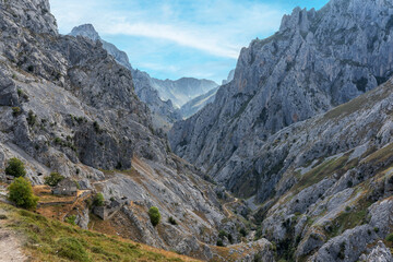 Stunning panoramic view of the dramatic rocky peaks and deep valleys of the Picos de Europa National Park in  Spain, showcasing rugged cliffs, narrow gorges. Popular destination for hiking, adventure.