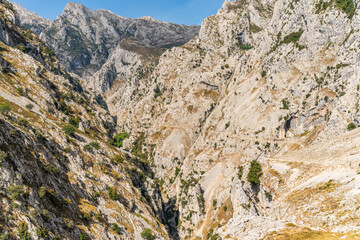 Stunning panoramic view of the dramatic rocky peaks and deep valleys of the Picos de Europa National Park in  Spain, showcasing rugged cliffs, narrow gorges. Popular destination for hiking, adventure.