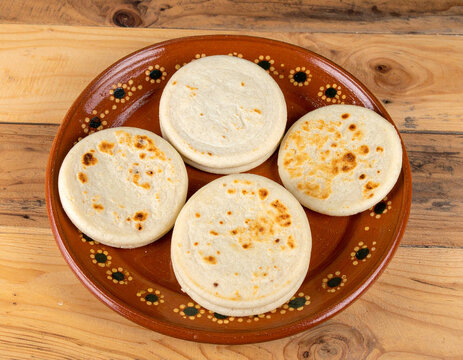 Pupusas, the thick corn tortillas filled with cheese, beans, or pork, arranged on a rustic plate, showcasing a popular Salvadoran staple food.