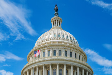 U.S. flag and the dome of the capitol in Washington, D.C. Blue sky with clouds.