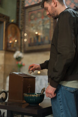 Modern Orthodox Christian man praying and lighting candles in a monumental Georgian church. A personal spiritual connection and moment of faith
