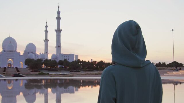 Close up Woman in traditional Arabic dress in Wahat Al Karama or Oasis of Dignity near Sheikh Zayed Grand Mosque in Abu Dhabi, showcasing cultural elegance and iconic Islamic architecture at sunset