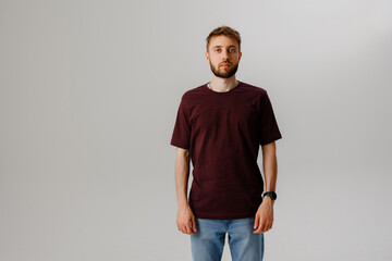 Young man standing confidently in casual clothing against a neutral background during a studio photoshoot