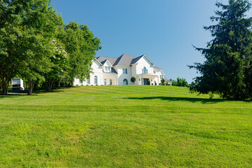 Large country white house and summer landscape with perfect lawn.
