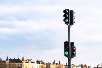 Traffic lights with twin heads and pale sky, standing over a distant city backdrop, evoking calm infrastructure, control systems, and modern street layout.