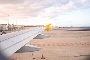 Airplane wing view during takeoff at a busy airport