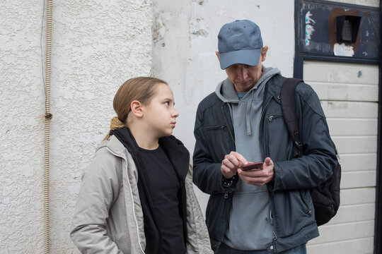 Sad daughter and her father using smartphone app outdoors - Powered by Adobe