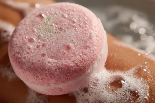 Close-up of pink bath bomb on arm with bubbling soapy water creating relaxation and gentle exfoliation during bathing routine. - Powered by Adobe